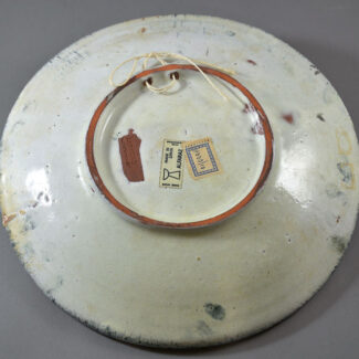 The backside of an Alfaraz pottery charger; the glaze is white with markings center.
