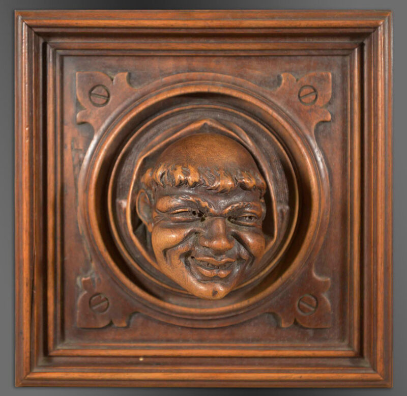Victor Aimone Carved Wall Panel Trompe L'oeil carved in wood depicting a monk's head peeping out of a circular architectural roundel set within a square panel.