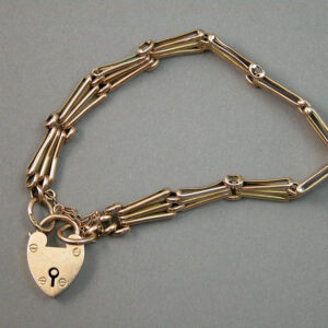 A chain link bracelet made of 9k yellow gold held together by a heart shaped gold locket