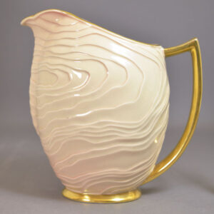 a modern form pitcher with contoured body, white glaze, andgilt handle and foot.