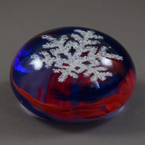 Caithness paperweight with a blue and red swirl around a suspended snowflake.