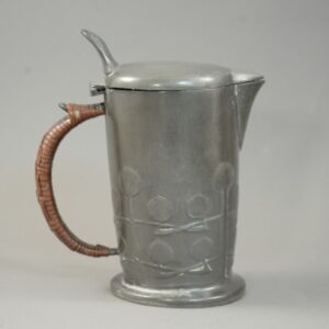 Liberty & Co hot water jug #0967 designed by Archibald Knox in pewter with a cane wrapped handle and seed pod decoration.